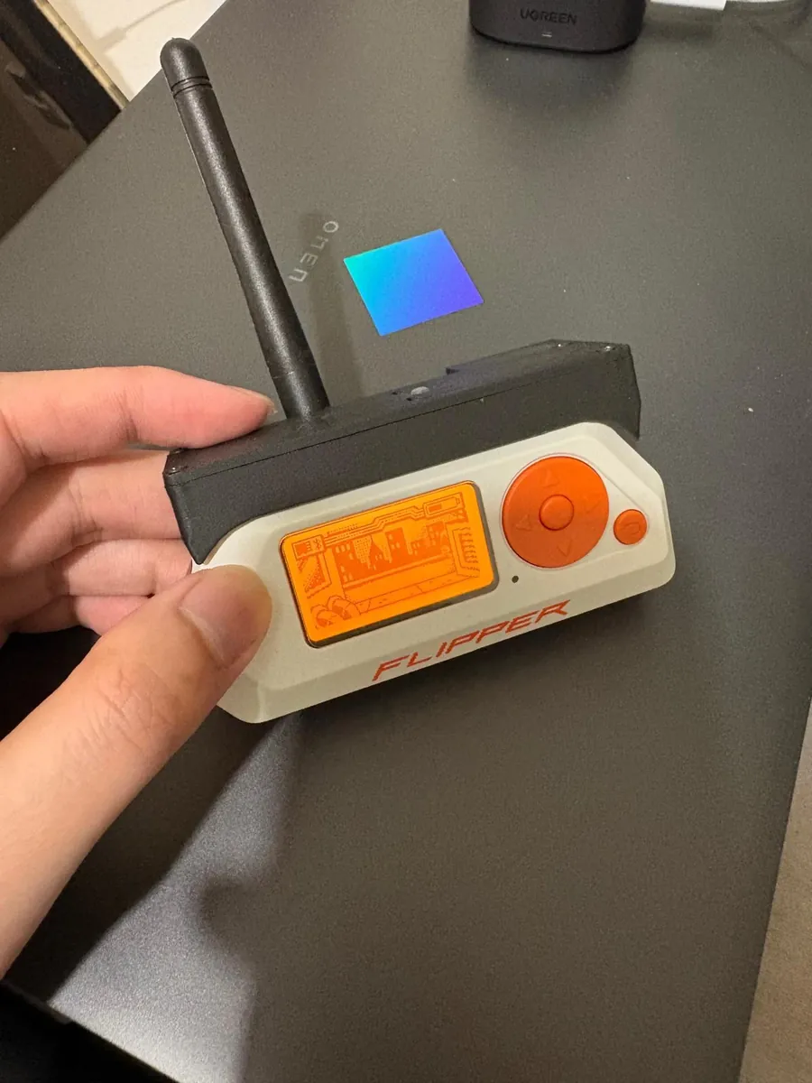 A hand holding a Flipper Zero with a Flipper Zero Dev Board Pro and an antenna attached on top